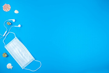 Protection mask, headsets and seashells. Vacation concept. Top view, copy space