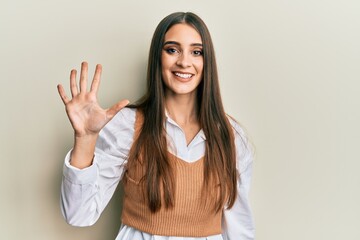 Beautiful brunette young woman wearing casual clothes showing and pointing up with fingers number five while smiling confident and happy.