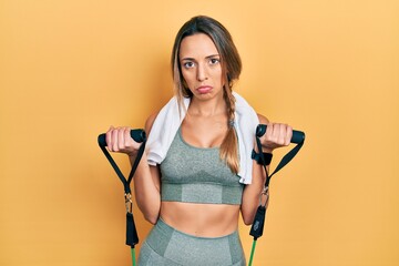 Beautiful hispanic woman training arm resistance with elastic arm bands depressed and worry for distress, crying angry and afraid. sad expression.