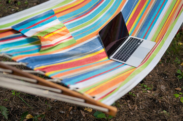 Laptop on a striped hammock. Freelancer remote work concept.