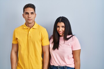 Young couple standing over isolated background smiling looking to the side and staring away thinking.