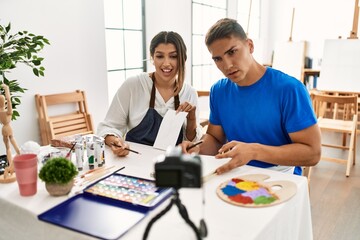 Two students smiling happy recording paint class using camera at art school.