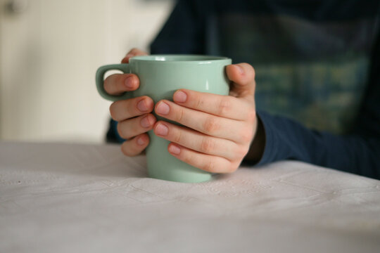 A young boy (child) holding a cup with both hands