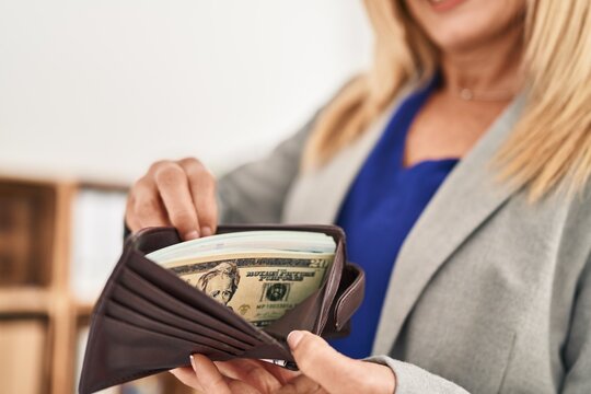Middle age blonde woman business worker showing wallet with dollars at office
