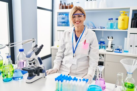 Middle age blonde woman working at scientist laboratory with a happy and cool smile on face. lucky person.