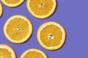 Fototapeta na wymiar Sliced fruit oranges in checkered pattern on violet background. Fruit background from a slice of oranges. Demonstrating very peri, color of 2022 year.