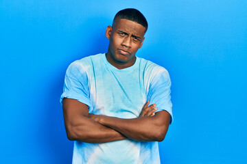 Young black man wearing tye die t shirt skeptic and nervous, disapproving expression on face with crossed arms. negative person.