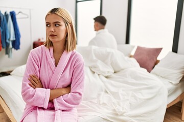 Young caucasian couple in conflict sitting on the bed at home.