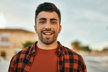 Young hispanic man smiling happy standing at the city.