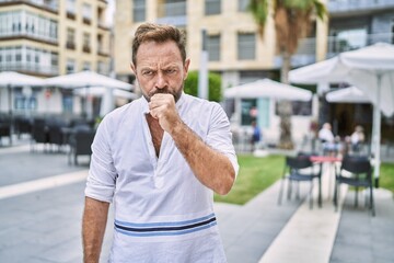 Middle age man outdoor at the city feeling unwell and coughing as symptom for cold or bronchitis. health care concept.