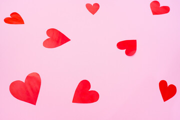 Red hearts on pink background, romantic paper cut concept, top view.