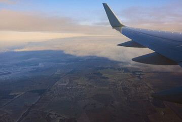 Obraz premium View to the wing of airplane in the sky. Travel and transportation concept