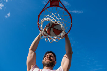 dunk in basket. slam dunk in motion. summer activity. smiling man with basketball ball