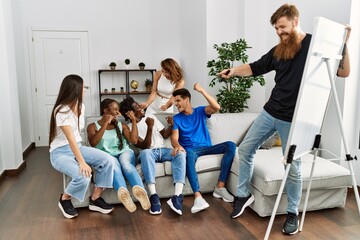 Group of young friends smiling happy playing drawing game at home.