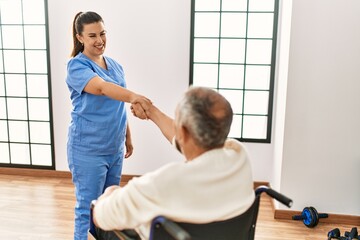 Senior man sitting on wheelchair  and geriatric nurse doing hand shake agreement, thanking for help