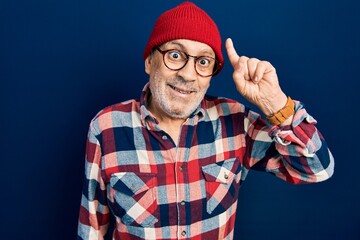 Naklejka premium Handsome mature man wearing hipster look with wool cap pointing finger up with successful idea. exited and happy. number one.