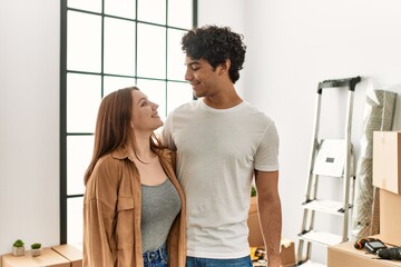 Young couple smiling happy and hugging standing at new home.