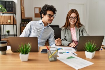 Two business workers smiling happy working using laptop at the office.