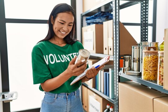 Young latin woman wearing volunteer uniform working at charity center