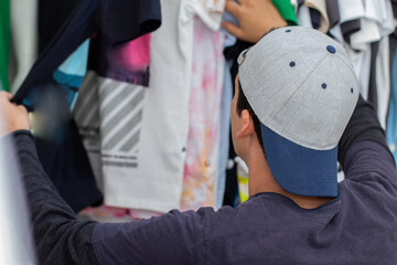 Young latin man wearing a youth cap shopping for clothes.