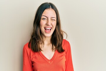 Fototapeta premium Young brunette woman wearing casual clothes winking looking at the camera with sexy expression, cheerful and happy face.