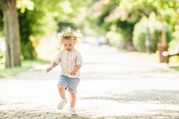 Cute little boy with curly blonde hair playing in park