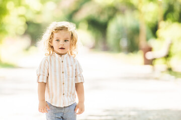 Cute little boy with curly blonde hair playing in park