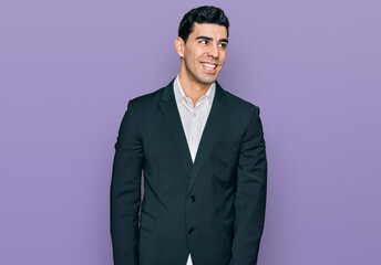 Fototapeta premium Handsome hispanic man wearing business clothes looking away to side with smile on face, natural expression. laughing confident.