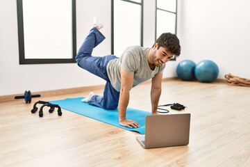 Young hispanic sporty man smiling happy having online sport class at gym center.