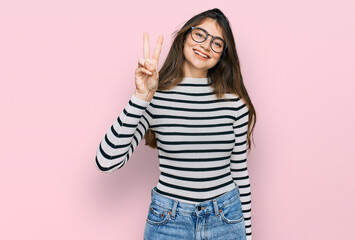 Young beautiful teen girl wearing casual clothes and glasses showing and pointing up with fingers number two while smiling confident and happy.