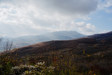Beautiful autumn landscape. Clouds, mountains, autumn forest.