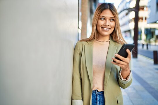 Young latin woman smiling confident using smartphone at street