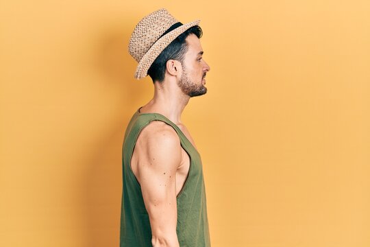 Young hispanic man wearing summer hat looking to side, relax profile pose with natural face with confident smile.