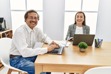Middle age man and woman business workers using laptop working at office