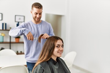 Fototapeta premium Young man cutting hair his girlfriend at home.