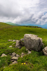 Fototapeta na wymiar beautiful landscape with green hills. huge boulders, stones and rocks on the grassy mountain slope. cloudy summer weather. scenic outdoor environment