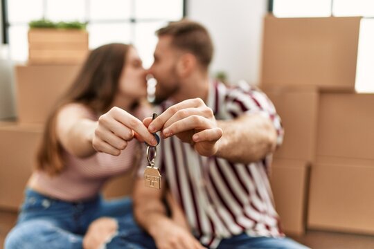 Young caucasian couple smiling happy holding key of new home.