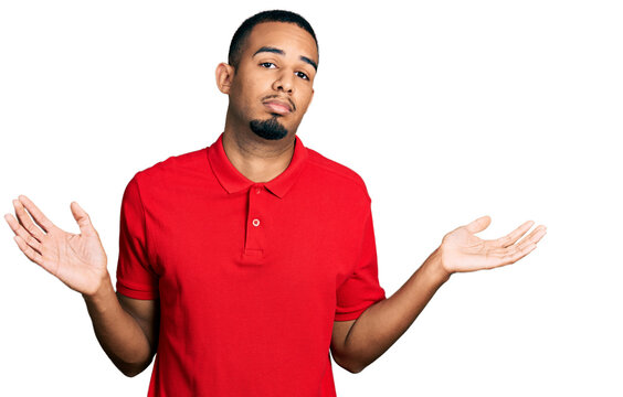Young african american man wearing casual polo clueless and confused with open arms, no idea and doubtful face.