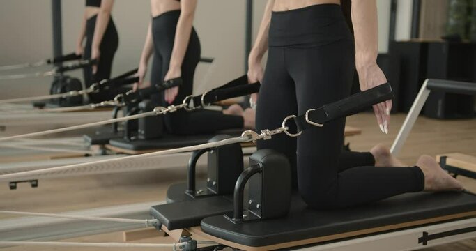 Three women doing pilates on a reformer bed