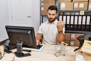 Handsome hispanic man working at small business commerce showing middle finger, impolite and rude...