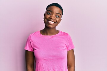 Young african american woman wearing casual pink t shirt with a happy and cool smile on face. lucky person.