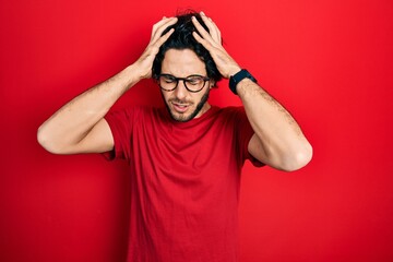 Handsome hispanic man wearing casual t shirt and glasses suffering from headache desperate and stressed because pain and migraine. hands on head.