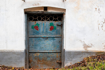Old metal door with grape pattern on old white wall