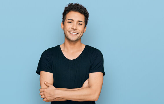 Young handsome man wearing casual black t shirt happy face smiling with crossed arms looking at the camera. positive person.