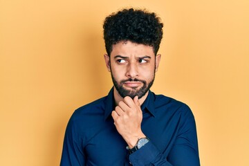 Young arab man with beard wearing casual shirt with hand on chin thinking about question, pensive...