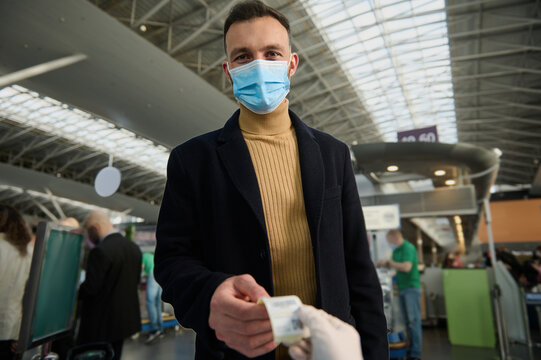 Handsome Young Man In A Protective Medical Mask Receives A QR Code After Being Tested Before Departure At The International Airport. Safe Flight And Travel During A Pandemic