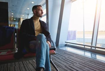 Handsome attractive man, confident businessman on business trip, sitting in the departure lounge,...