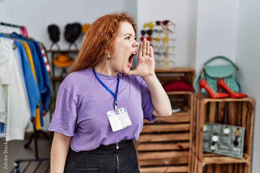 Sticker Young redhead woman working as manager at retail boutique shouting and screaming loud to side with hand on mouth. communication concept.