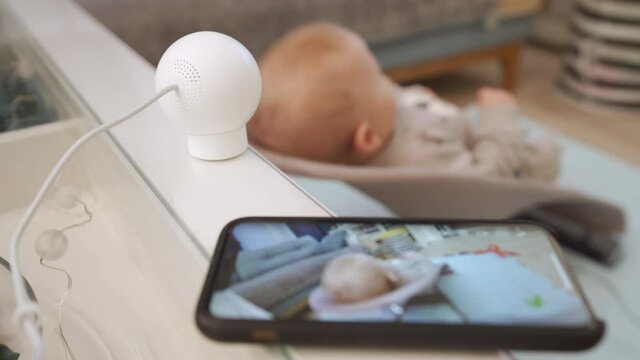 Smart IP camera is installed in the childrens room, indoor security camera works as a baby monitor. Parents watching baby in real-time on smartphone screen. High quality 4k footage