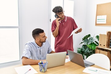 Two business workers talking on the smartphone and using laptop working at the office.